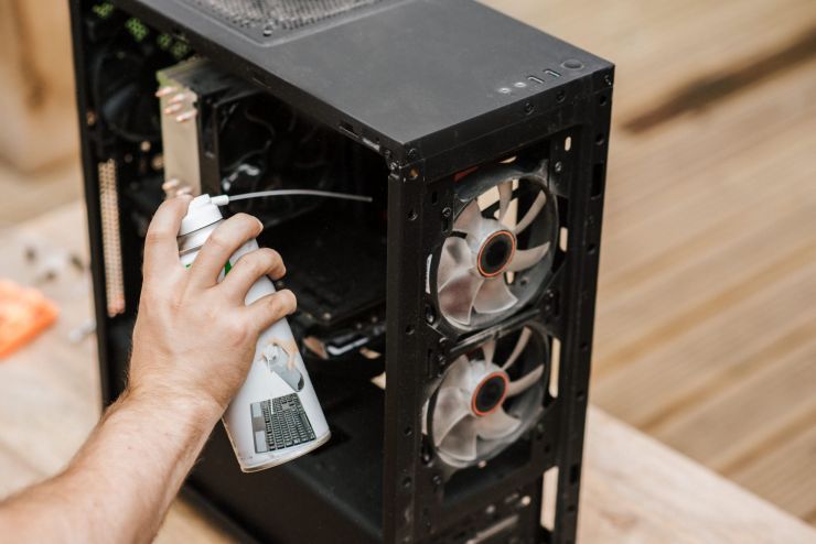Service tech cleaning dust from computer in Regina